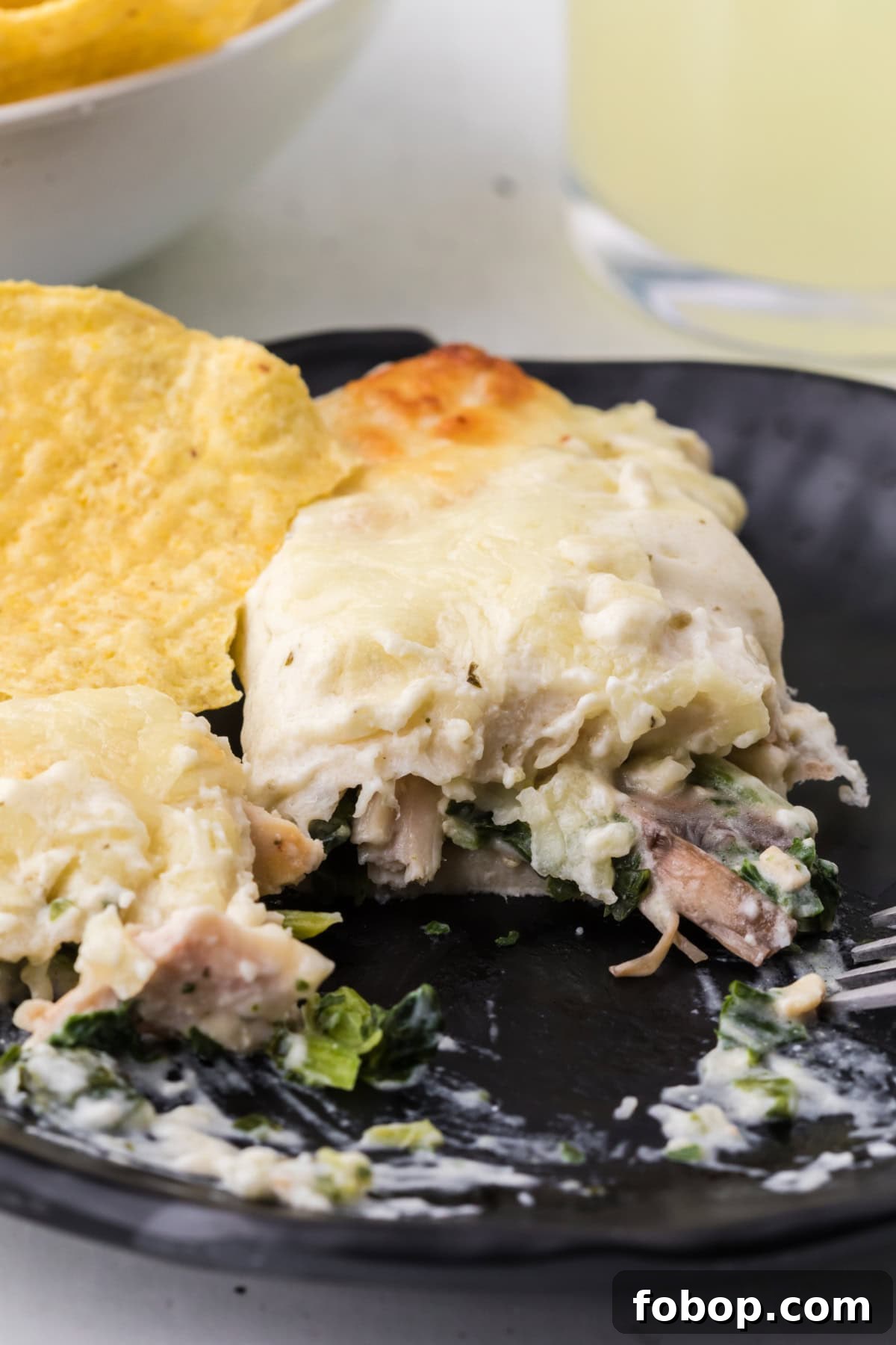 Plate of Creamy Chicken, Spinach & Mushroom Enchiladas serving of creamy chicken spinach and mushroom enchiladas on plate cut into