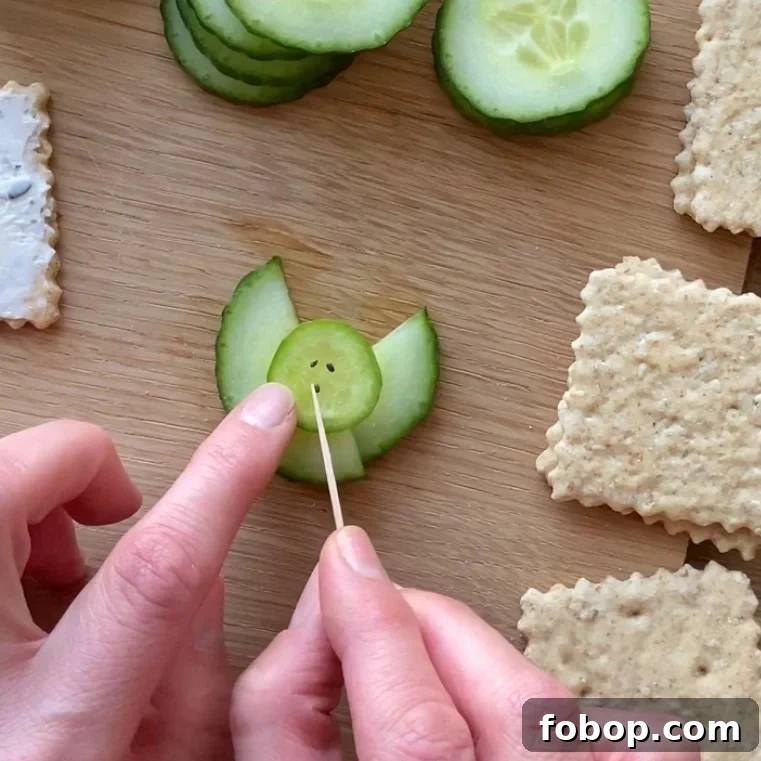 A person uses a toothpick to place seeds on a cucumber slice.