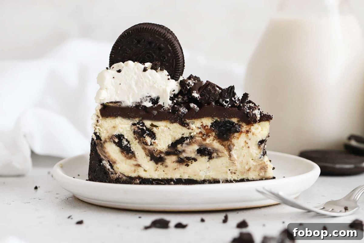 slice of gluten-free Oreo cheesecake topped with chocolate ganache, chopped Oreo cookies, and whipped cream