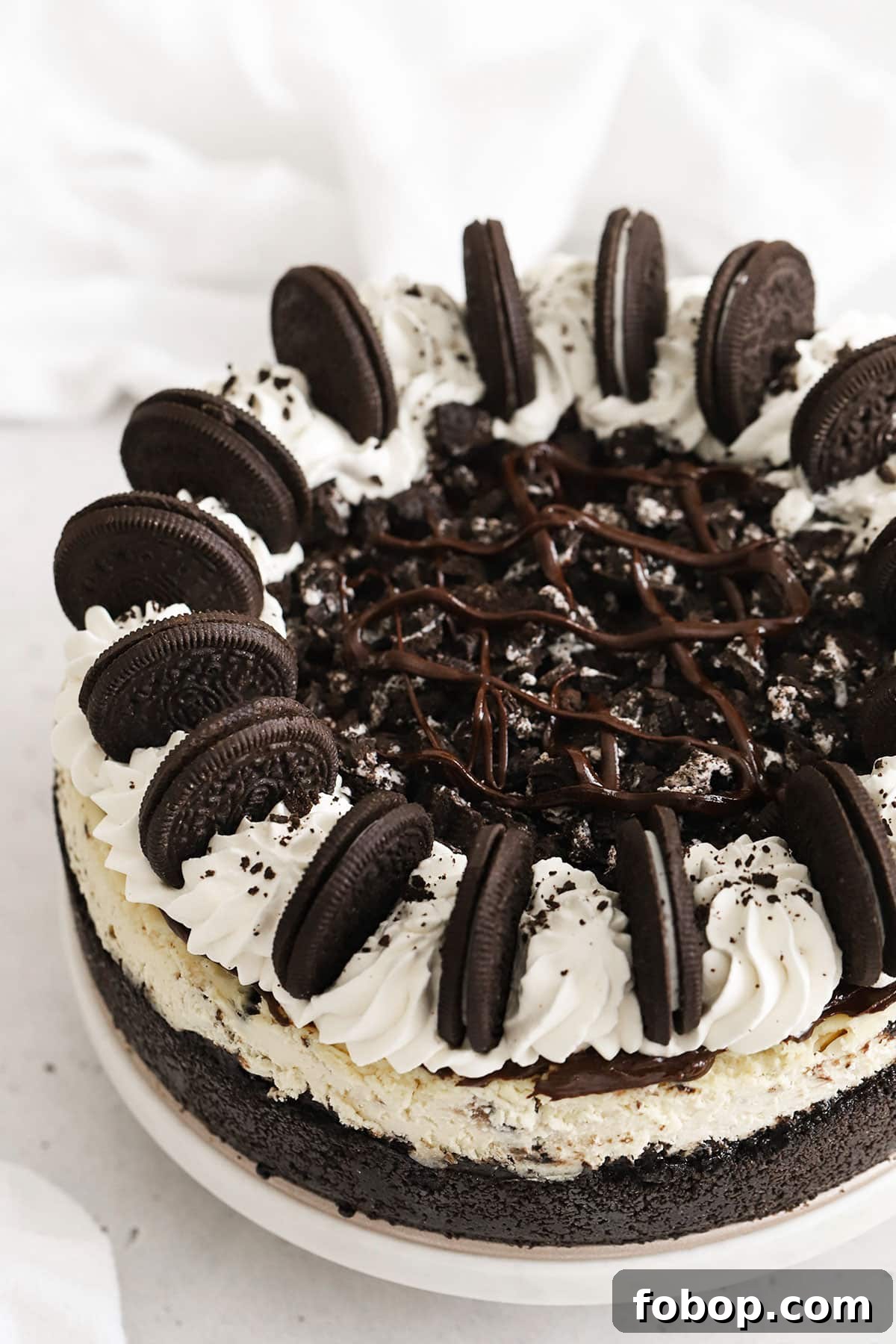 Whole Gluten-Free Oreo Cheesecake Topped With Whipped Cream Swirls, Chocolate Ganache & Oreo Cookies