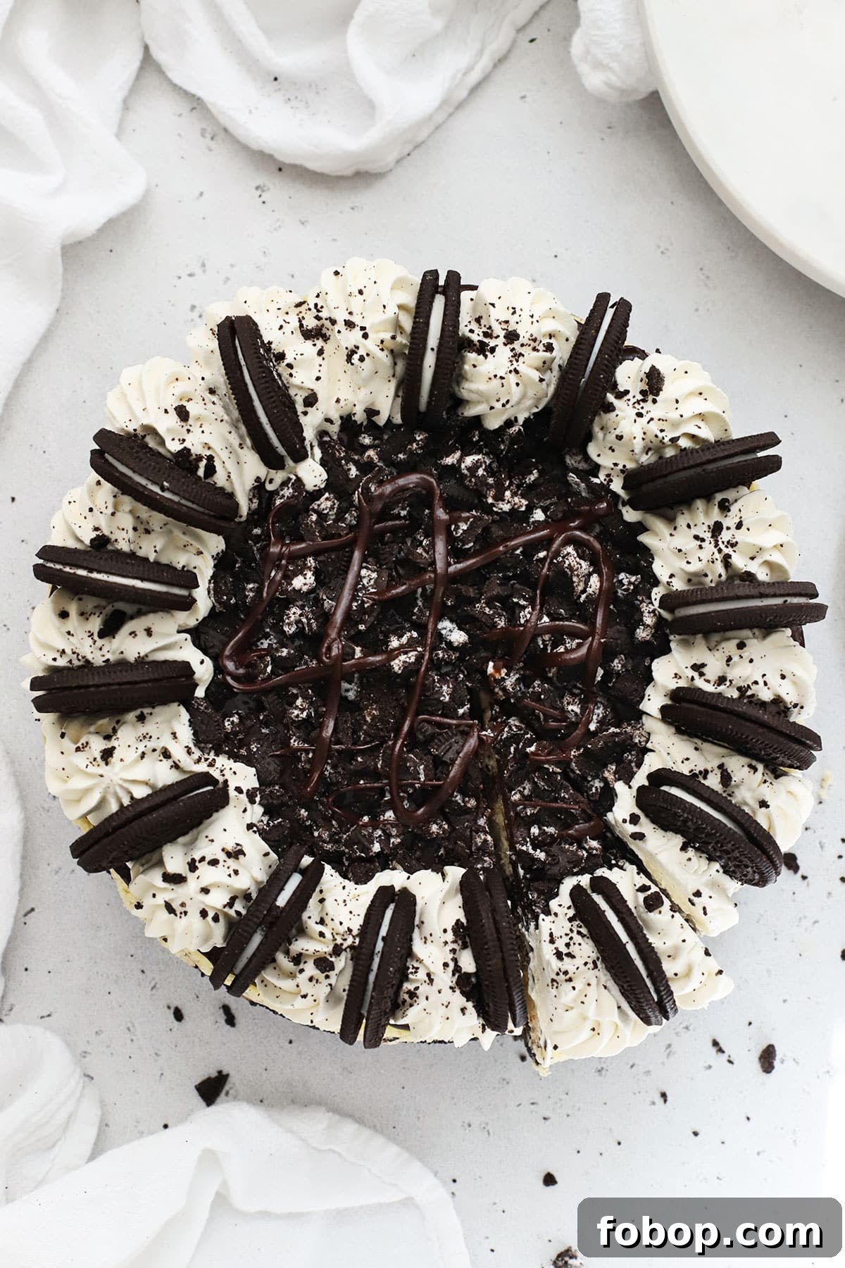Whole Gluten-Free Oreo Cheesecake Topped With Whipped Cream Swirls, Chocolate Ganache & Oreo Cookies