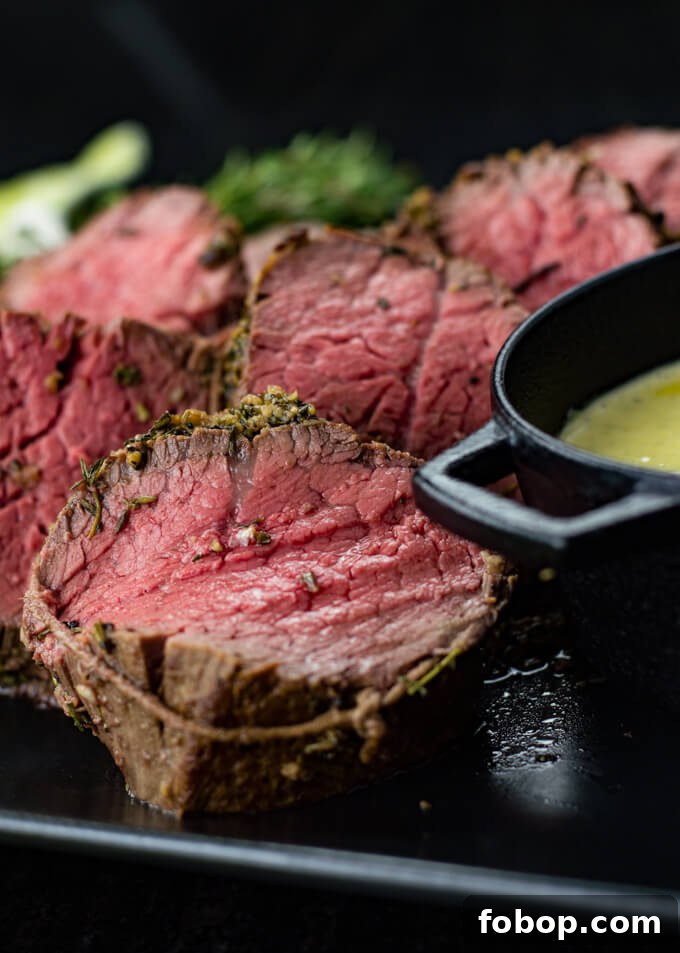 Perfect Beef Tenderloin Roast Recipe for Tender, Juicy Results 2 Slices of rare beef tenderloin next to a black bowl of homemade bearnaise sauce.