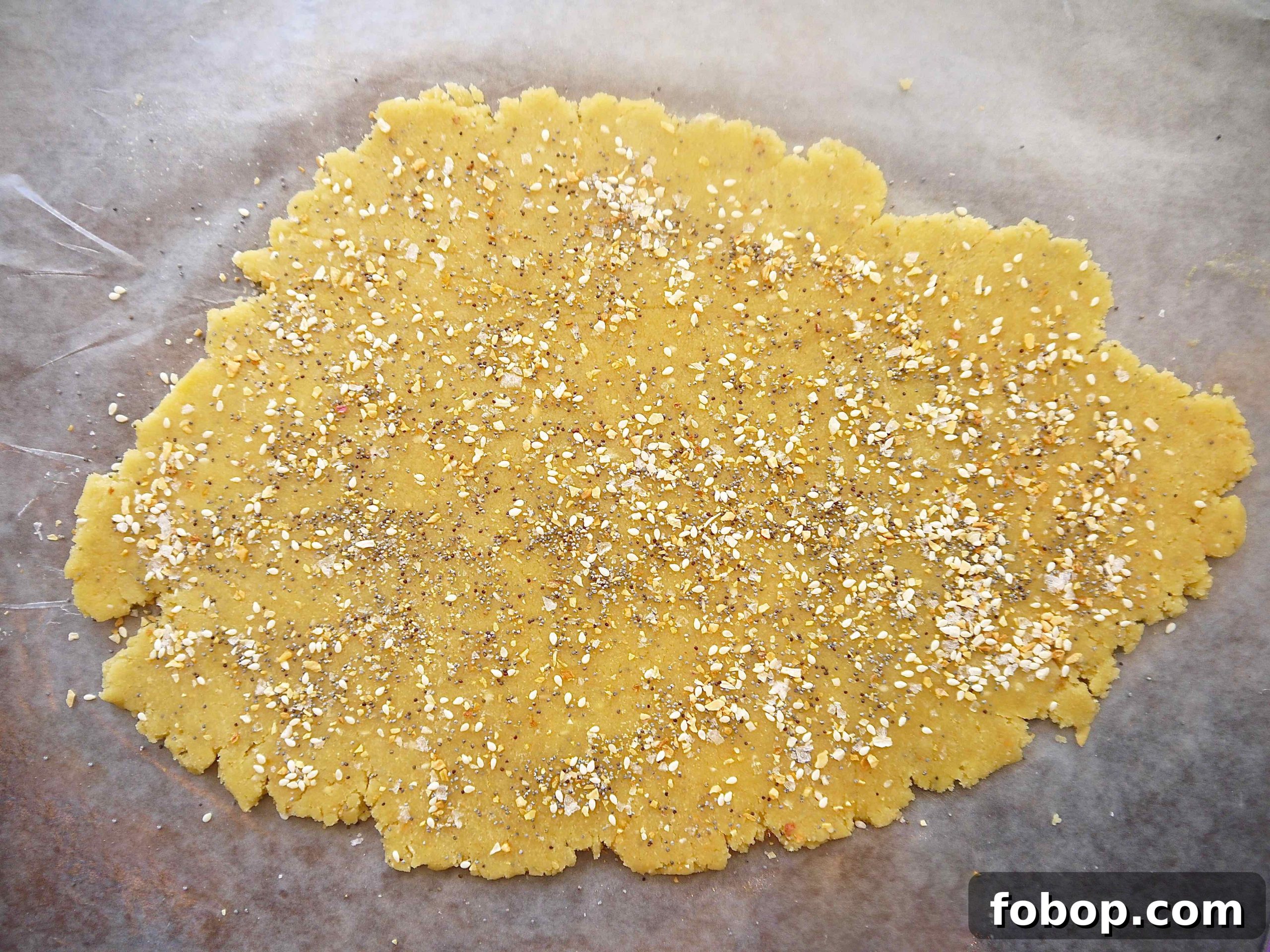 Almond flour cracker dough rolled out flat with bagel seasoning on top.