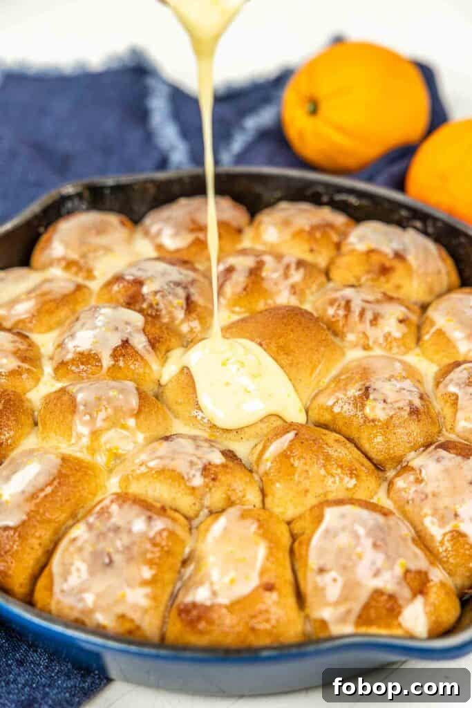 Citrus-Glazed Orange Pull-Apart Dinner Rolls 4 pouring icing over orange rolls in a skillet