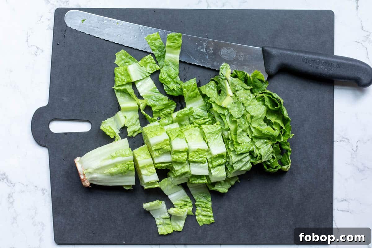 Perfect Side Salad Recipes to Complement Any Meal 4 head of romaine lettuce cut into slices on cutting board with large serrated knife.