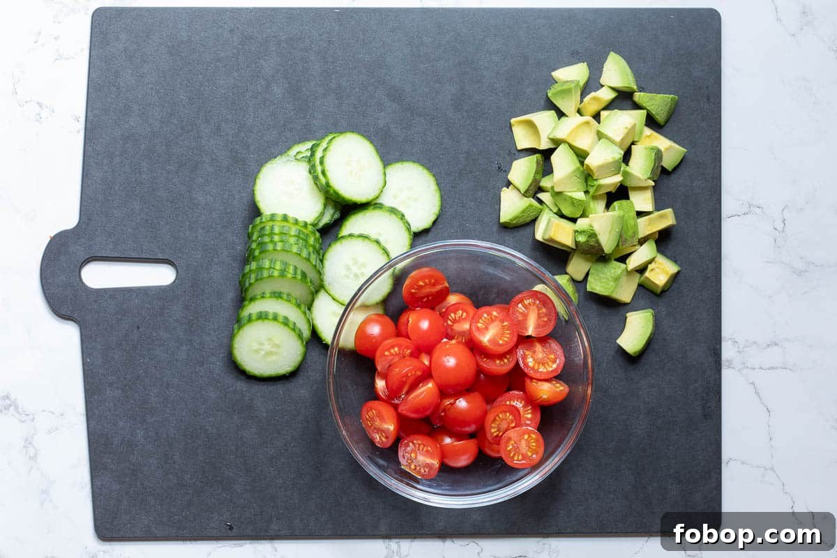 Perfect Side Salad Recipes to Complement Any Meal 5 sliced cucumbers, cubed avocado chunks, and halved cherry tomatoes on cutting board.