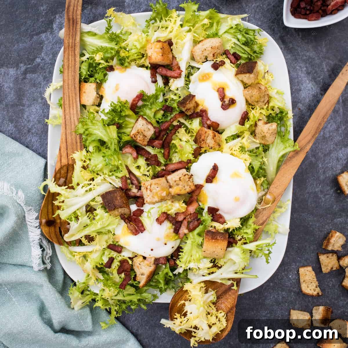 platter of frisee salad with serving utensils and napkin