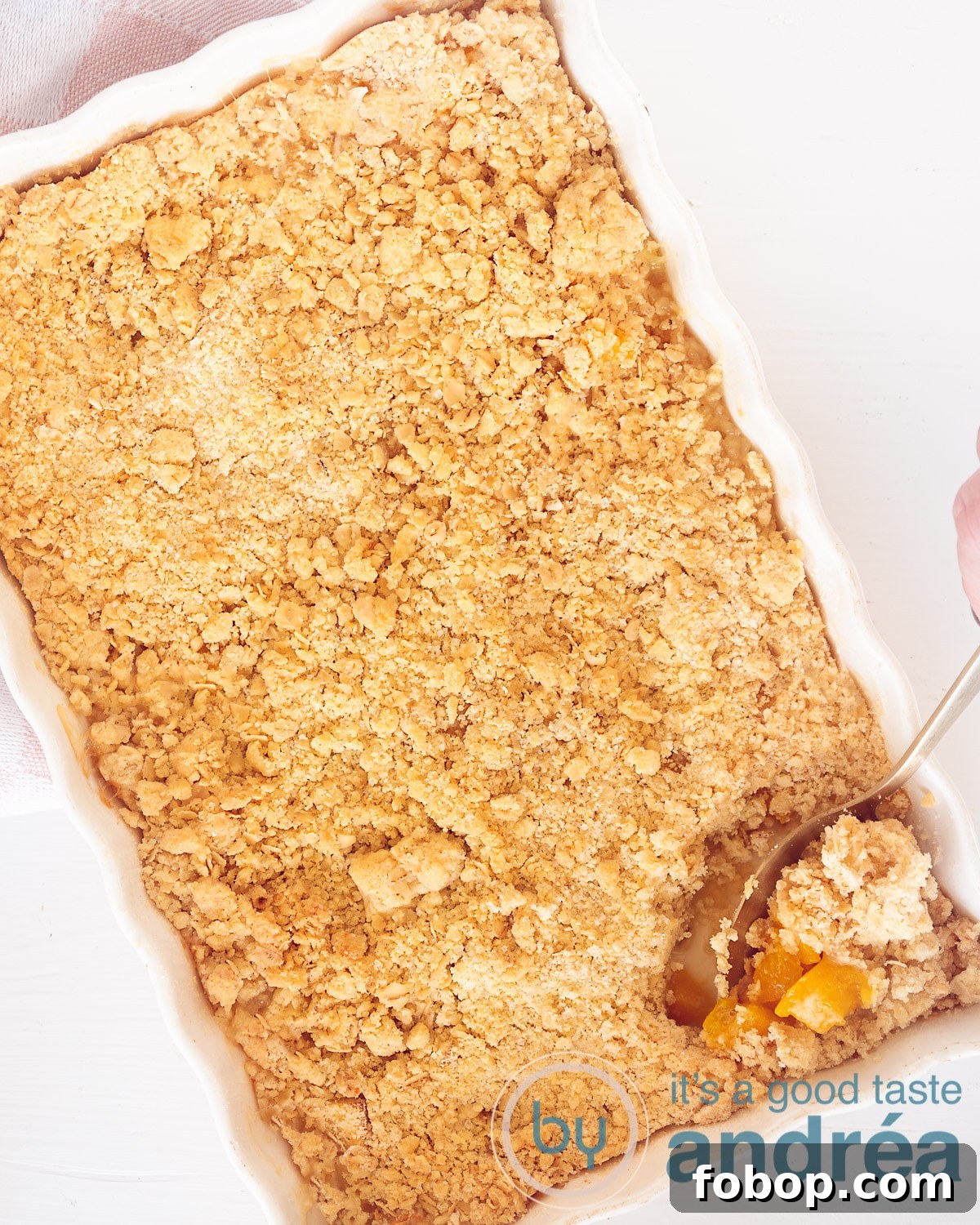 Apple and Peach Crumble Recipe: Simple Oven-Baked Fruit Crisp 2 A photo from above with a white oven dish with a crumble, a spoon out at the bottom right