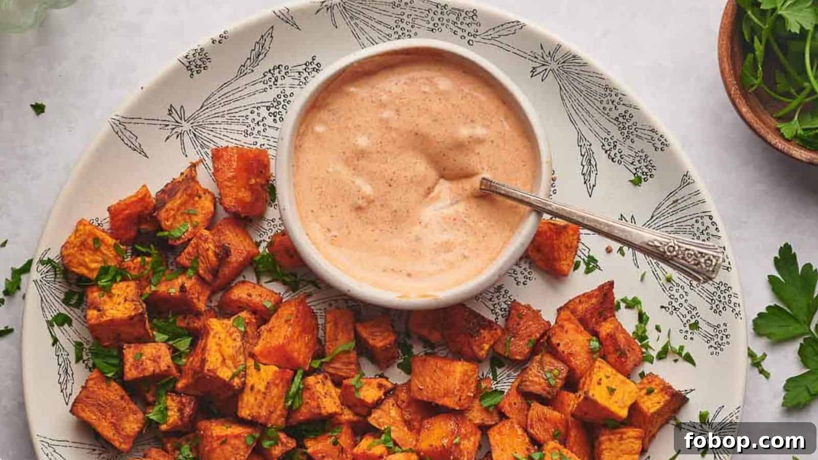 Dipping sauce in a small bowl surrounding by sweet potato cubes.