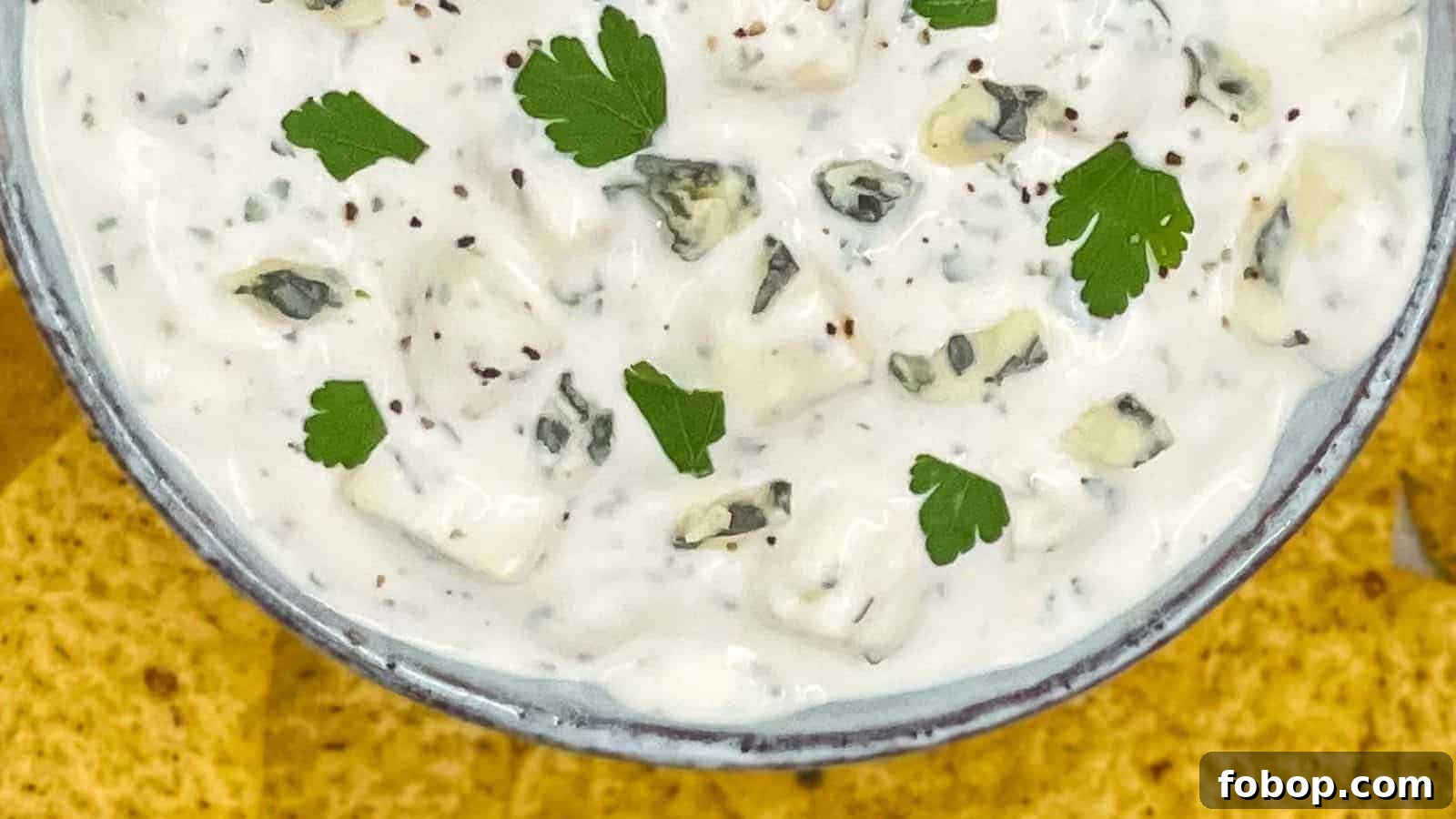 Blue cheese dressing in a serving bowl, you can see chunks of cheese and parsley.