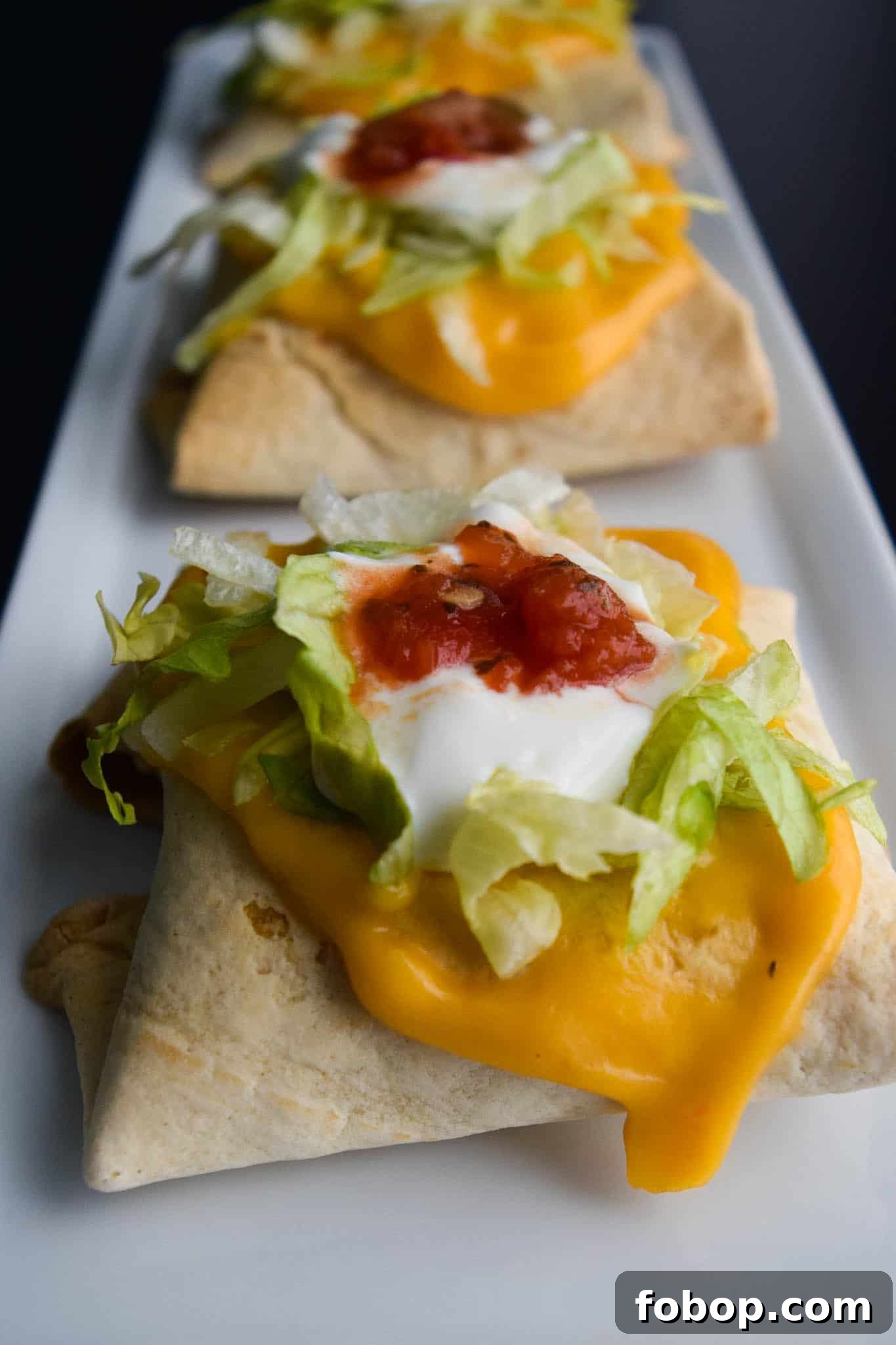 Baked Chimichangas with Guilt-Free Cheesy Sauce on white platter ready to be served close up view
