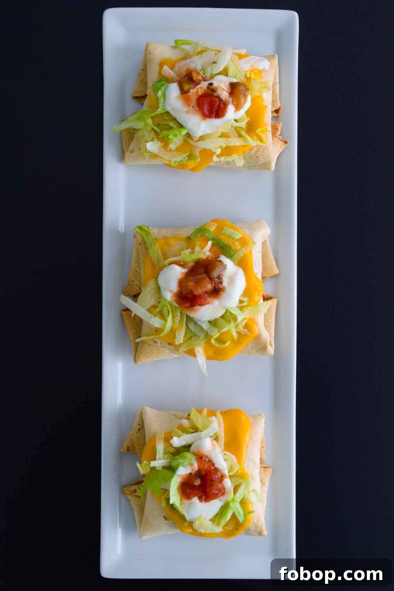 Baked Chimichangas with Guilt-Free Cheesy Sauce on white platter ready to be served overhead shot