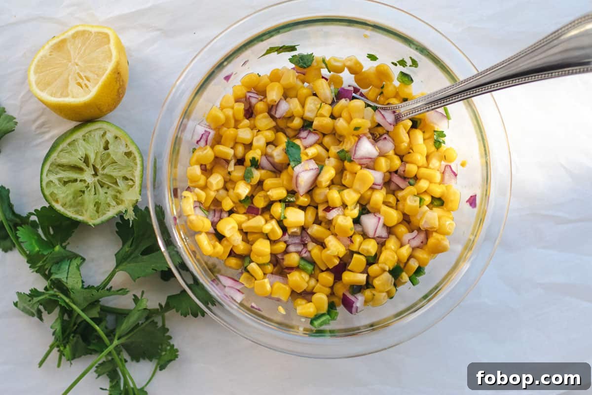 corn salsa in a glass bowl with a spoon to mix