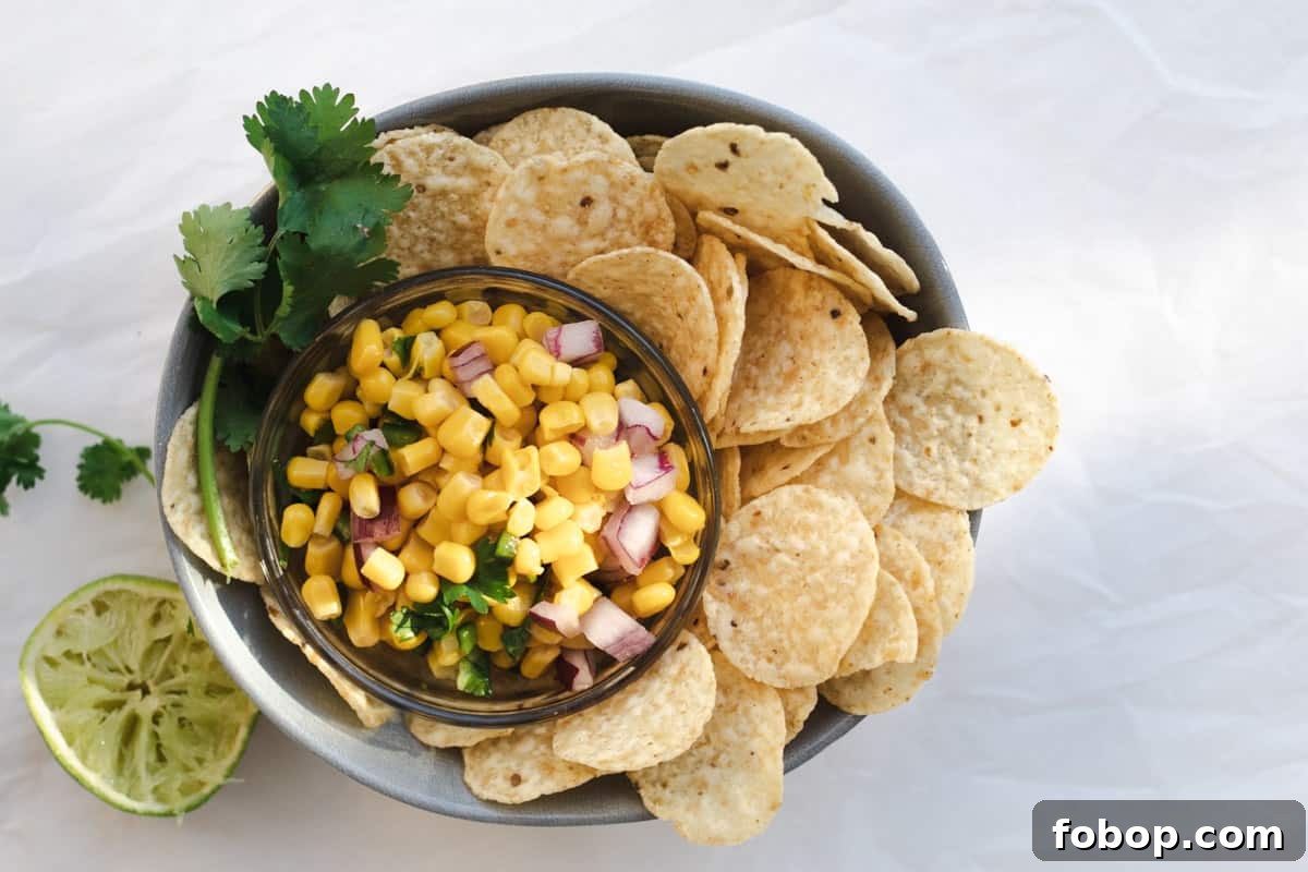 corn salsa in a bowl with chips and cilantro garnish