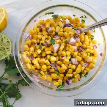 corn salsa in a glass bowl with a spoon to mix