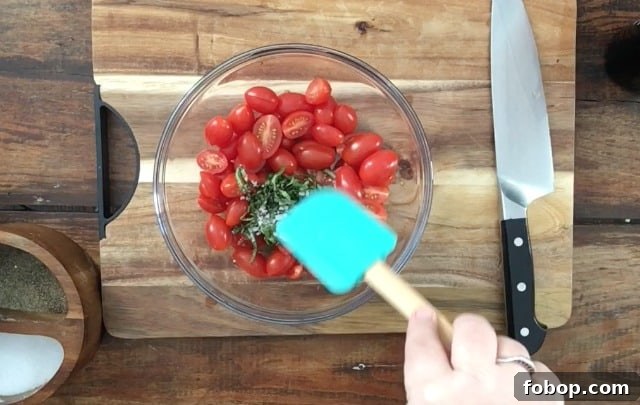 Summer cherry tomato salad with blue spatula in glass bowl on cutting board