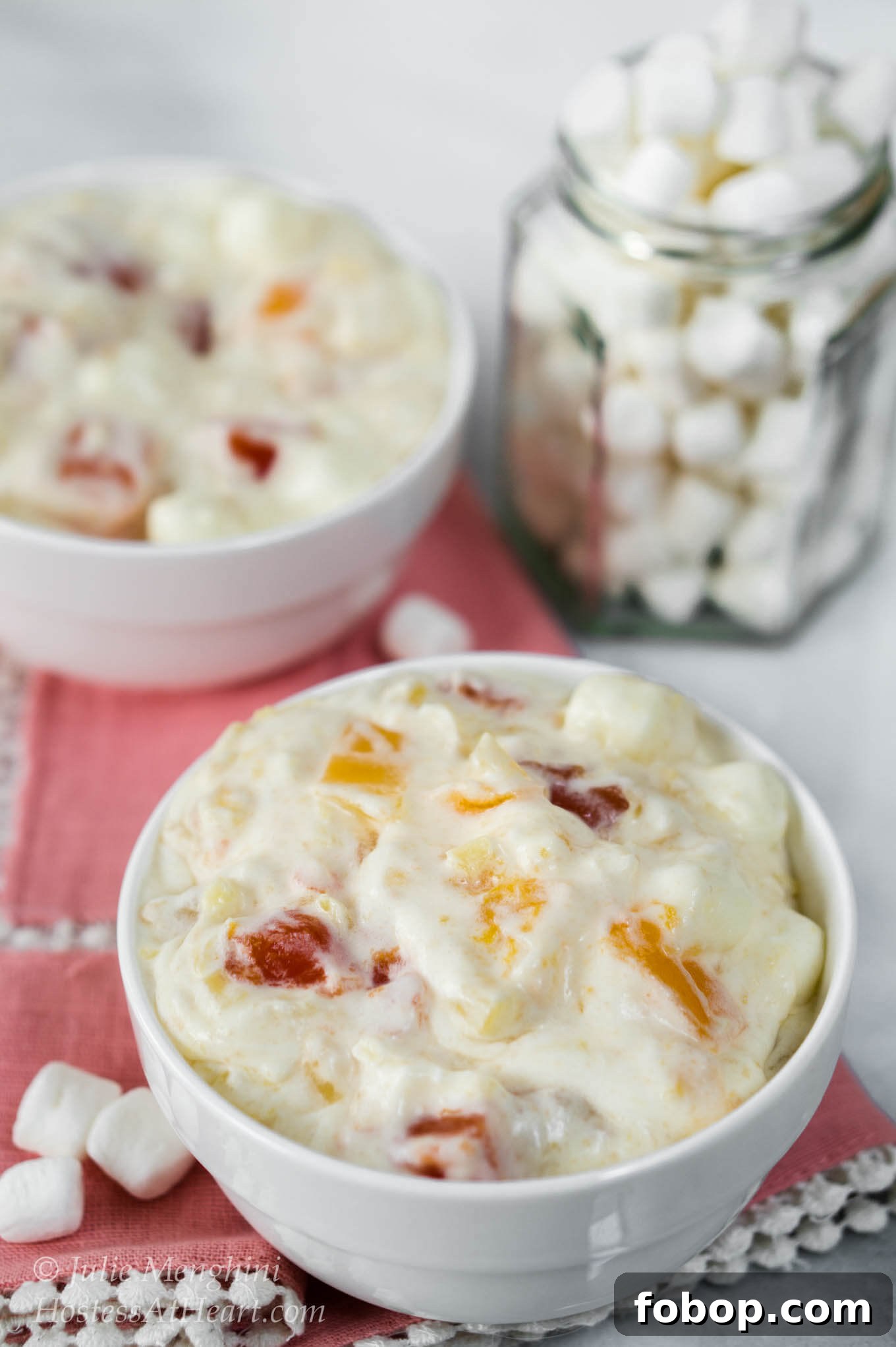 2 bowls of Tropical Fruit Cocktail Salad with a jar of marshmallows